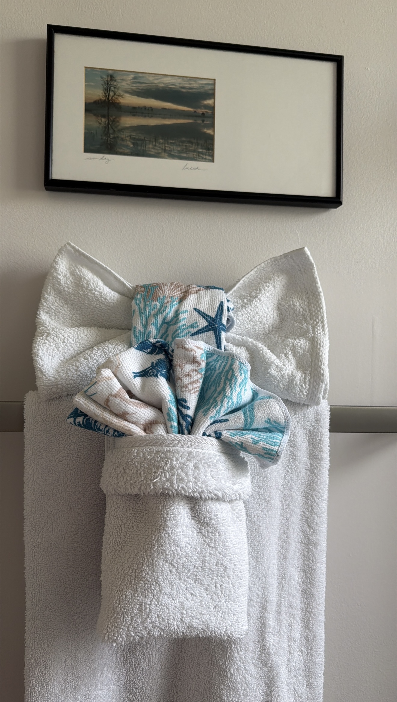 White bath towels arranged with a blue coastal hand towel in a decorative fold