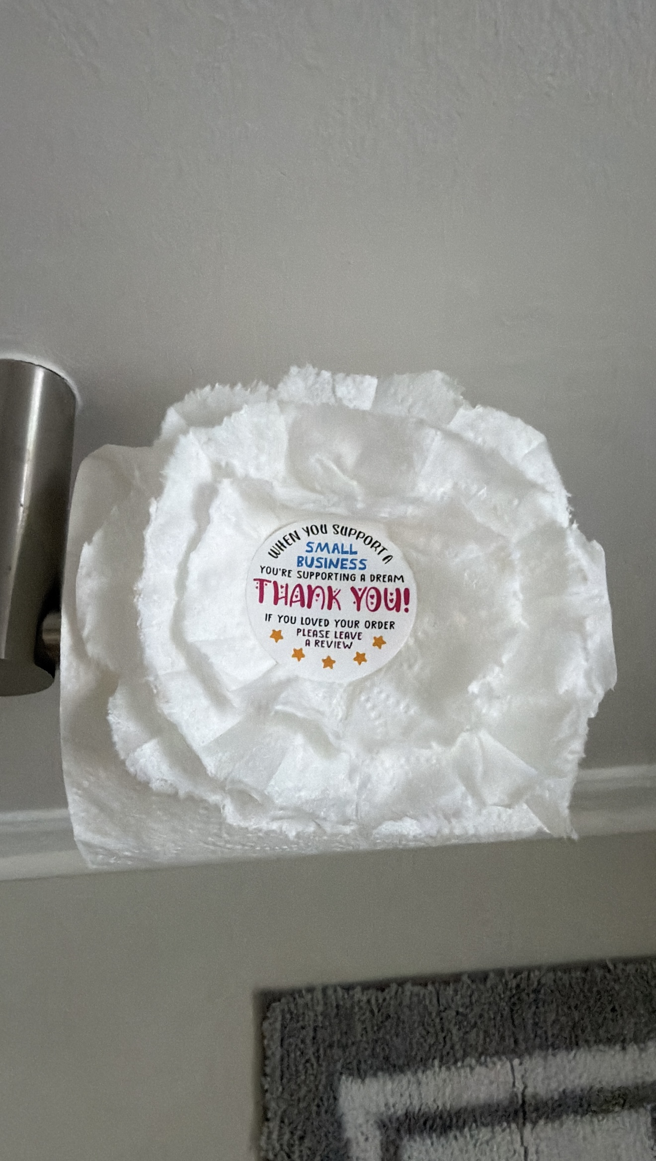 A decorative folded toilet paper detail with a small-business thank-you sticker
